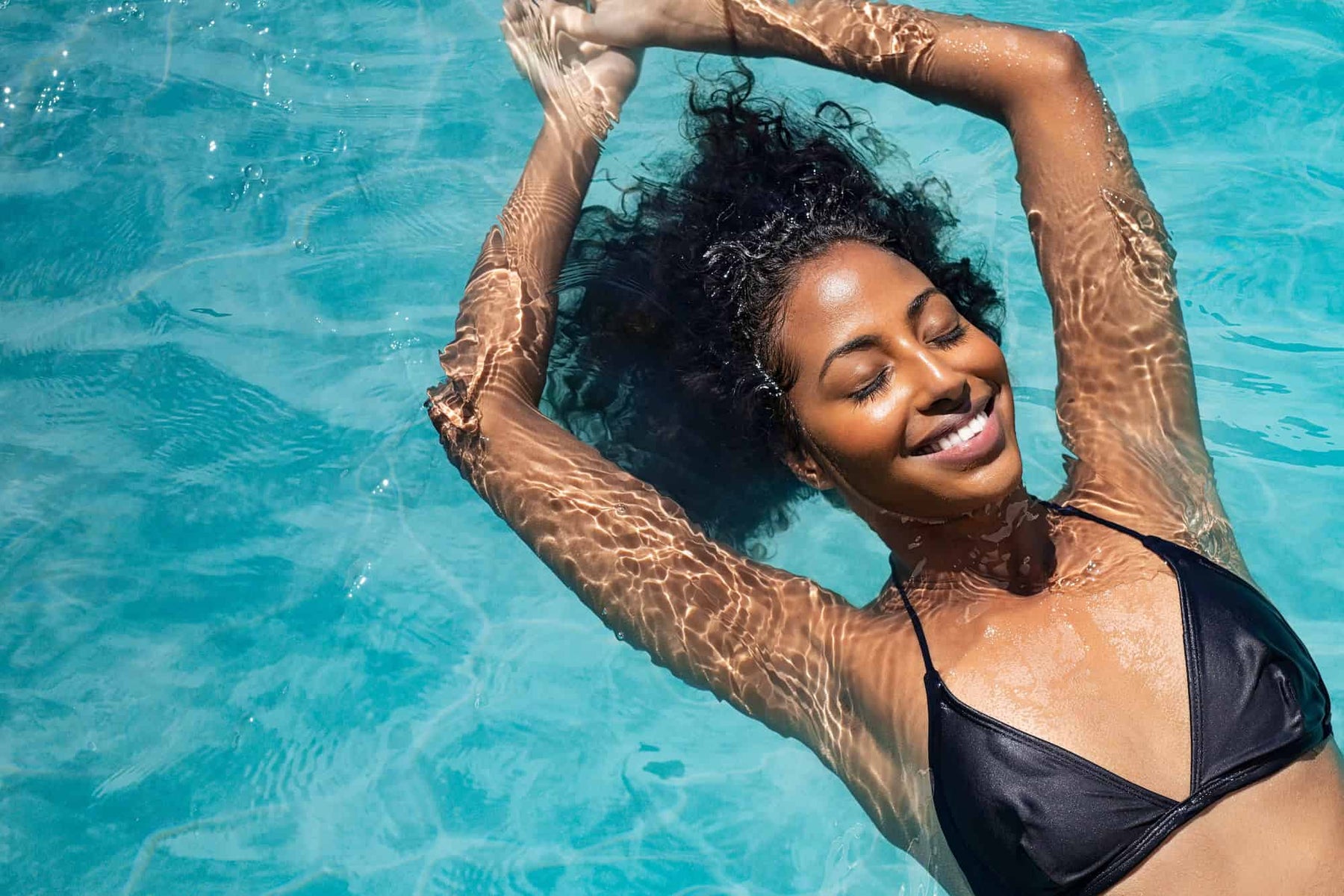 Smiling woman floating on back in water of floatation tank in London