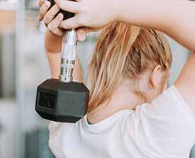 Woman lifting dumbbell over head before a float therapy session