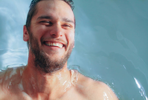 Smiling man floating on back in water of floatation tank in London