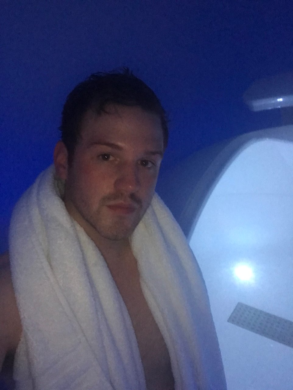 Man with towel around neck standing outside floatation tank in London spa